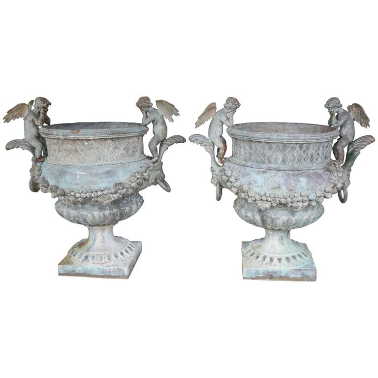Grand scale planters made of bronze in a verde patina. Winged angels Sit along each side facing inward. A foliate garland drapes the main body of the planters. Vintage with just the right amount of aging.
